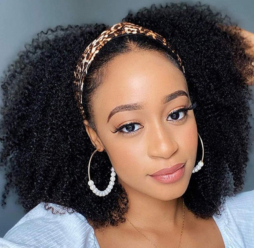Woman with curly hair wearing a leopard print headband and hoop earrings against a neutral background